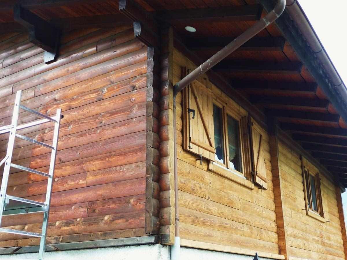 Chalet en rondins de bois, échafaudage contre la façade pendant la lasure.