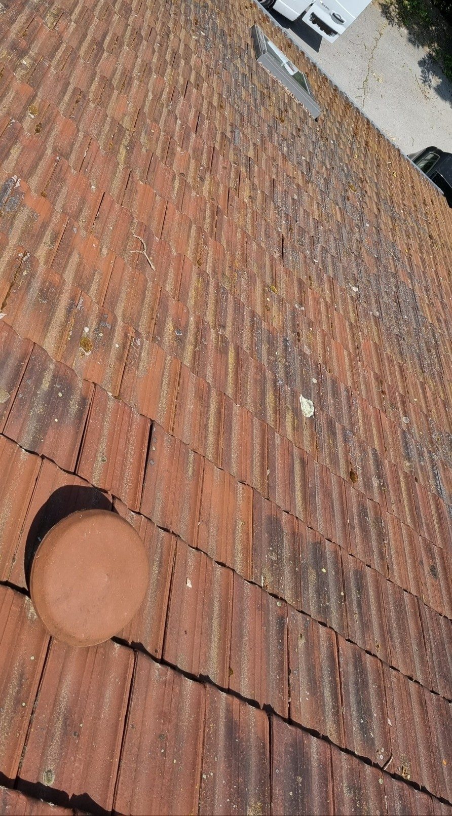 Rangées de tuiles anciennes sur un pan de toit, vues depuis le haut.