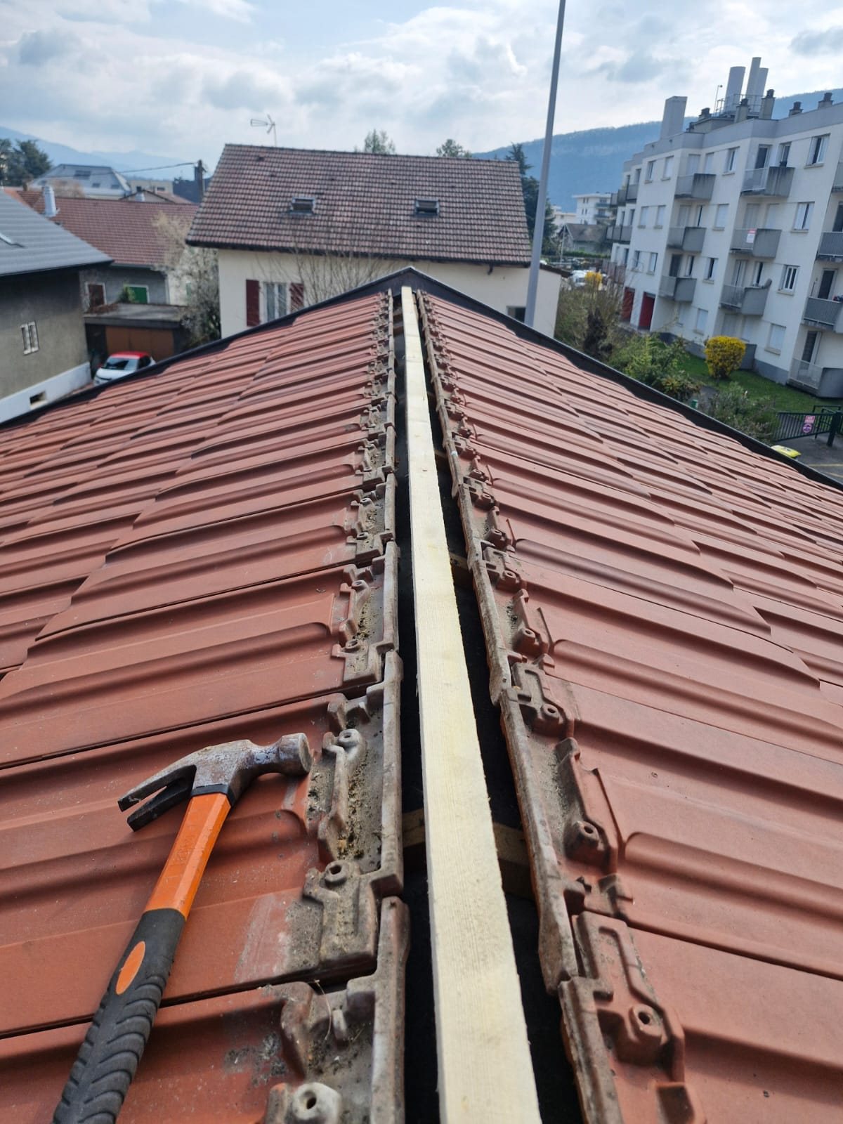 Pose des tuiles faîtières, marteau de couvreur posé sur le toit.